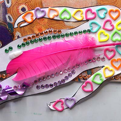 A pink feather laying across a paper cut out body