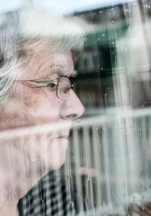 An older woman looking out a window